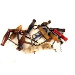 A large collection of vintage and modern wooden handled corkscrews, all of similar design, some with