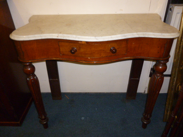 A Victorian mahogany marble top consul table, of serpentine form with single frieze drawer