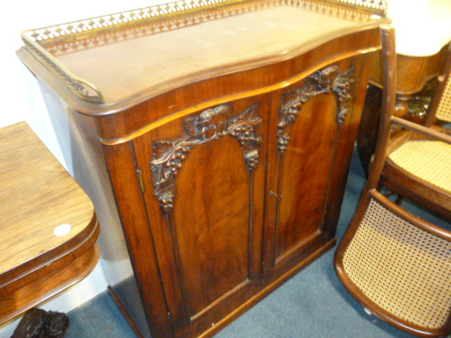 A Victorian serpentine chiffoneir, having applied head and grape vine decoration to doors, with