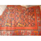 A red ground woolen carpet runner, the central panel with floral decoration, surrounded by a multi-