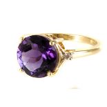 A 9ct gold amethyst and diamond three stone ring, the large round cut amethyst in tall four claw