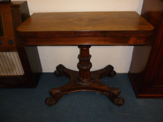 A William IV rosewood fold over pedestal card table, the lappet carved pillar surmounts a