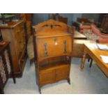 An Arts and crafts oak bureau cabinet, with pierced top rail and shelf, above fold down compartment,