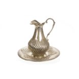 A Middle Eastern white metal ewer and stand, the jug and circular plate with embossed gadrooning,