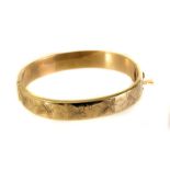 A 9ct gold bangle, one half with engraved leaf designs, hallmarked, approx 14.8g