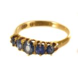 An 18ct gold and gem set five stone ring, having blue sapphire style graduating stones in hallmarked