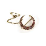 A pretty ruby and diamond brooch, in the form of a crescent set with round cut red stones and