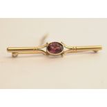 A 9ct gold bar brooch set with purple-re