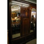 An Edwardian triple wardrobe inlaid with mirrored doors and two drawers under.