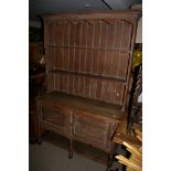 A limed oak dresser with a raised back and open shelves with cupboards under