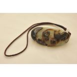 A carved jade two tone pendant in the form of a stylized animal
