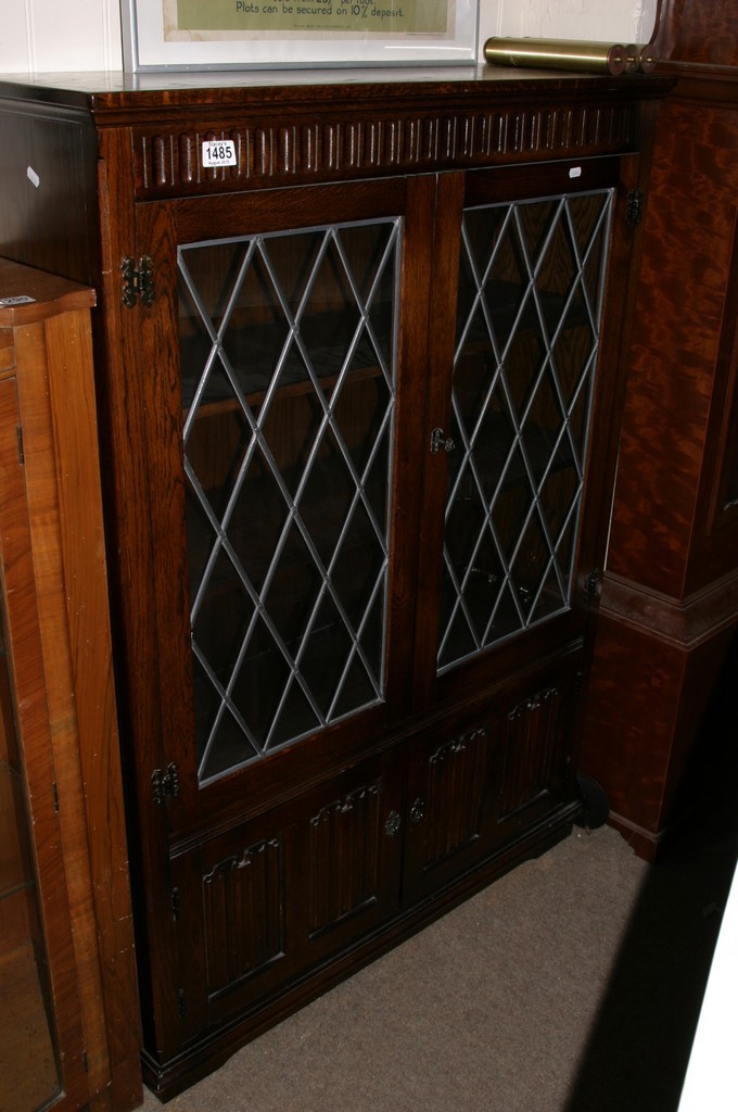 An oak bookcase with a pair of lead light glazed doors