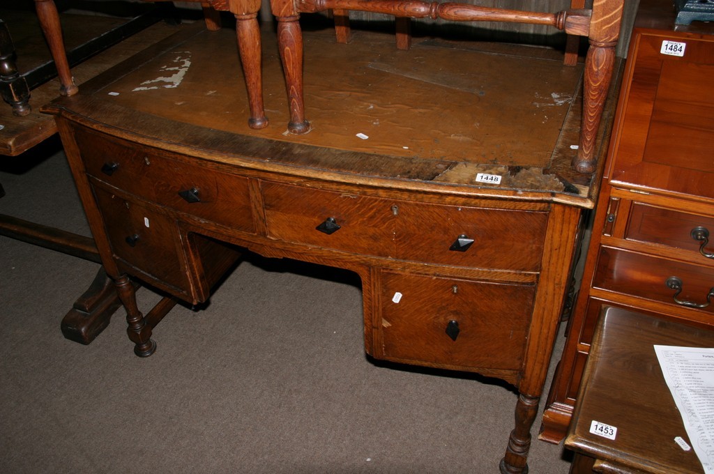 An oak desk with a leather inset top above draws on turned legs