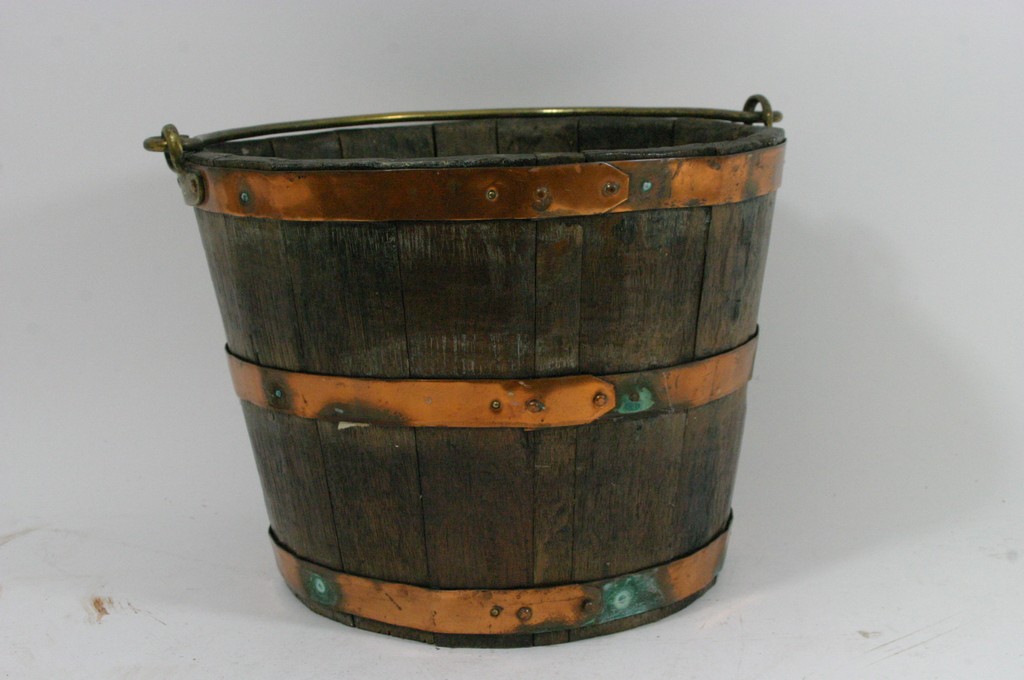 An oak copper bound bucket with brass swing handle