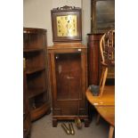 A large continental walnut clock with a square brass dial with glass front and visible pendulum and