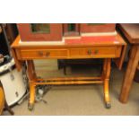 A reproduction leather topped drop leaf table with two drawers and two faux drawers and raised on