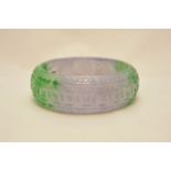 A 20th century two tone colour jade bangle with carved decoration