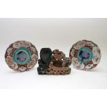 A carved soapstone ornament together with a pair of Imari plates of scalloped form.