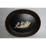 An oval Japanese lacquer plaque decorated with figures in a boat.