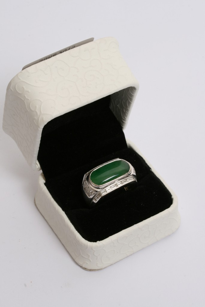 A 18ct white gold ring inset with jade stone surrounded by diamonds with testing certificate.