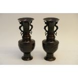 A pair of Oriental bronze vases (some damage) having trumpet shaped necks above squat inverted