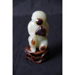 A carved jade monkey on wooden stand,