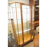 A bow fronted shop display cabinet fitted with two glass shelves and parquetry base,