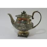 A silver teapot with raised floral relief,
