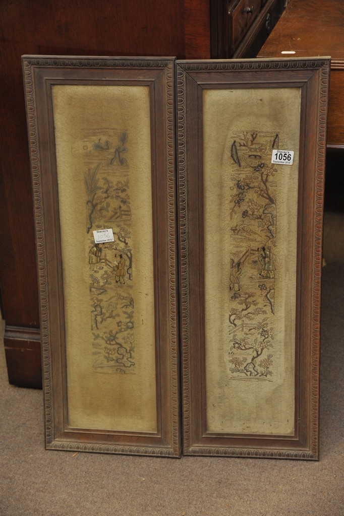 A pair of framed and glazed Chinese silk sleeves depicting figures in a garden setting.