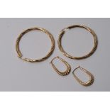 A large pair of gold hoop earrings and one other pair of gold hoop earrings