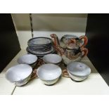 A decorative Japanese tea set, two teapots, five cups and saucers, with dragon overlaid decoration