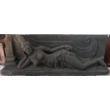 An Indonesian carved volcanic stone sculpture of a reclining topless Buddha on a plinth,