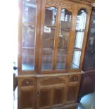 A glass framed display cabinet with single door to base and carved decoration to top