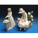 Two Nao figures comprising girl cutting a cake and girl on a bench with doves