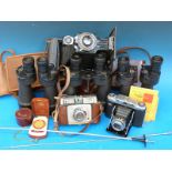 A collection of vintage binoculars and cameras including Zeiss Ikonta,