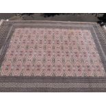 A large wool rug with multiple geometric borders with four rows of 10 guls on a pink ground (315cm