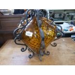 A cast iron framed amber glass hanging lamp, the glass with dimpled decoration and bulbous in form,