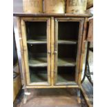 An oriental bamboo and lacquer display cabinet with three shelves behind double doors (H100 x
