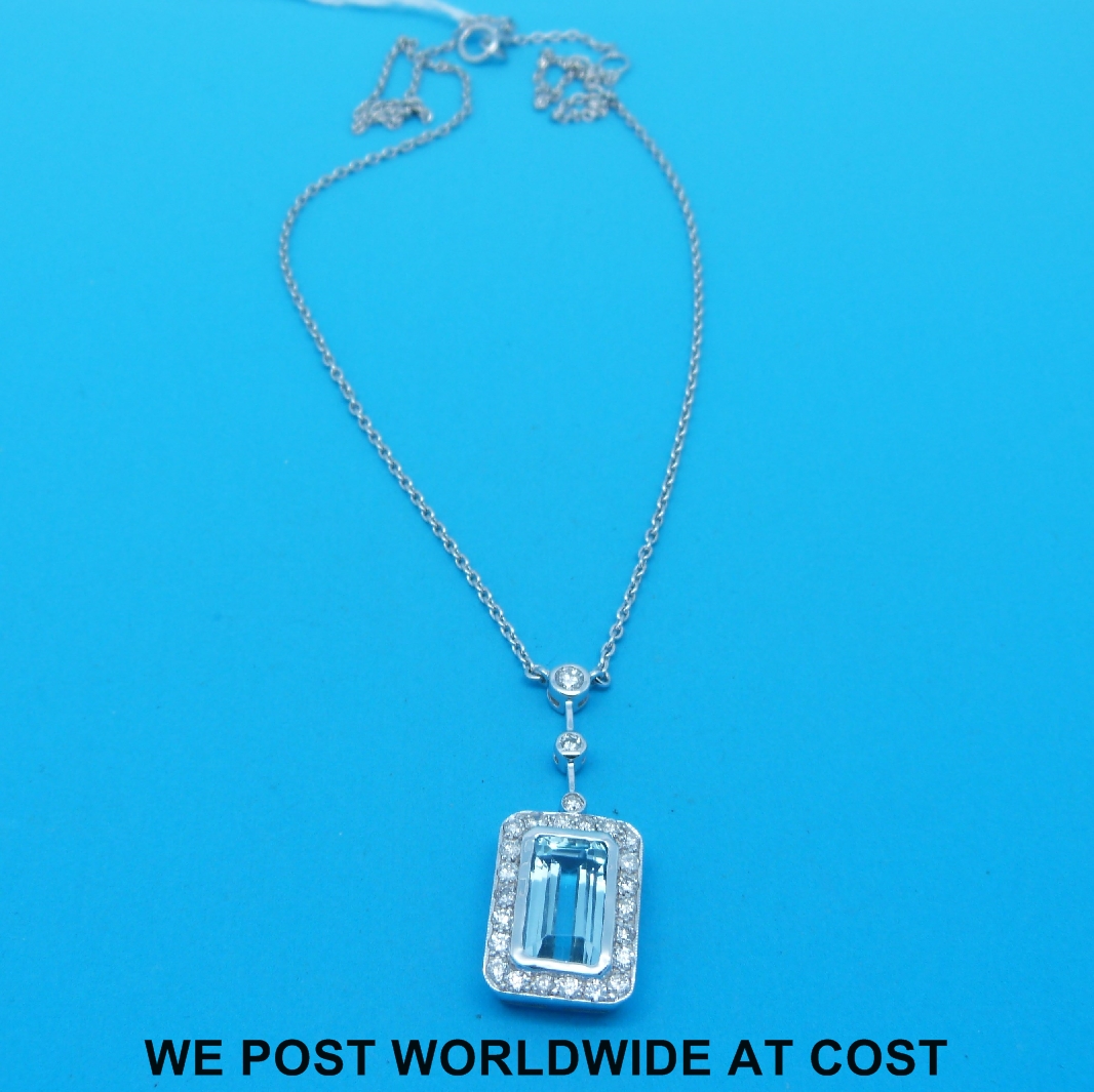 A white metal necklace marked 750 set with an emerald cut aquamarine surrounded by diamonds