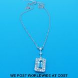 A white metal necklace marked 750 set with an emerald cut aquamarine surrounded by diamonds