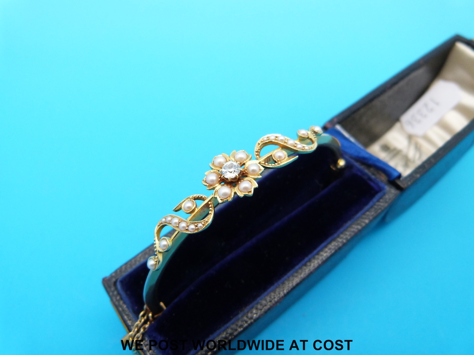 An Edwardian gold bangle set with a diamond and seed pearls in a floral design, - Image 2 of 3