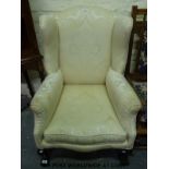 An upholstered wing back armchair raised on carved ball & claw feet