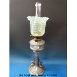 A vintage oil lamp with decorative cast reservoir leading to a fluted column supported by putti