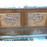 A Chinese elm desk sideboard the cupboard panels carved with three people by a bridge and houses