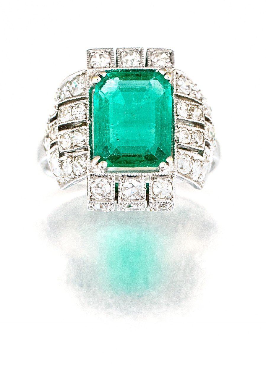 Art Deco emerald and diamond ring claw-set to the centre with an emerald-cut emerald weighing