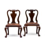 A pair of George II style mahogany side chairs each with waisted scroll side supports flanking a