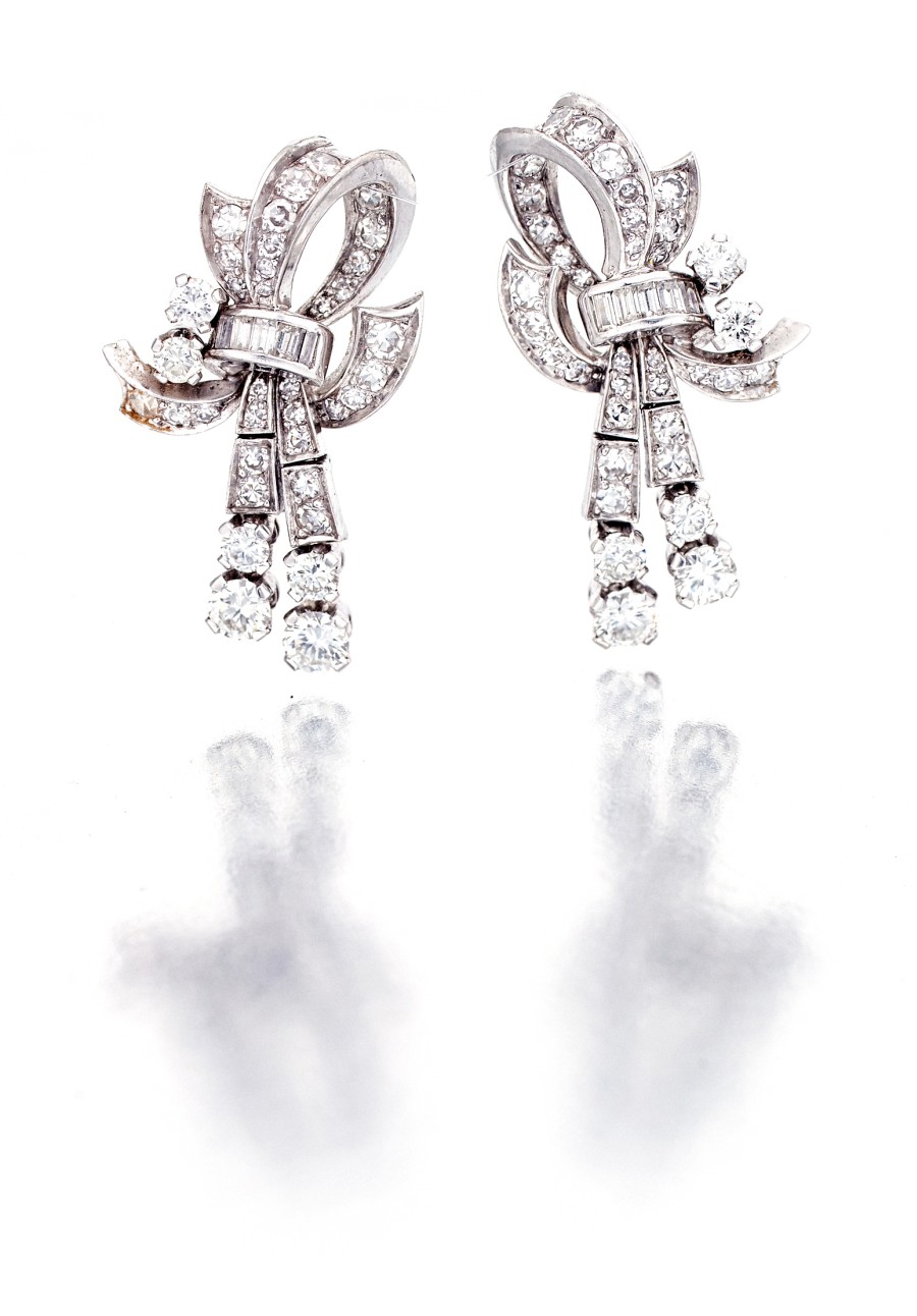 Pair of diamond earrings, 1950s designed as a ribbon with an articulated drop, claw- and channel-set