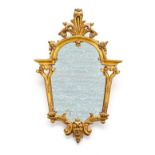 An Italian giltwood mirror the shaped plate with arched and foliate cresting, pierced and scroll