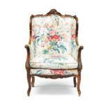 A French upholstered and walnut bergère the shaped frame carved with c-scroll and leaf crestings,