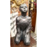 A black painted sculpture of a kneeling